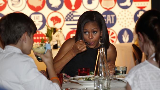 U.S. first lady Michelle Obama eats as she participates in a cooking demonstration at the James Beard American Restaurant with Italian and American middle school students in Milan, Italy, Wednesday, June 17, 2015.  Michelle Obama is in Milan on the second leg of a European trip that puts an international spin on her core initiatives. (AP Photo/Antonio Calanni)