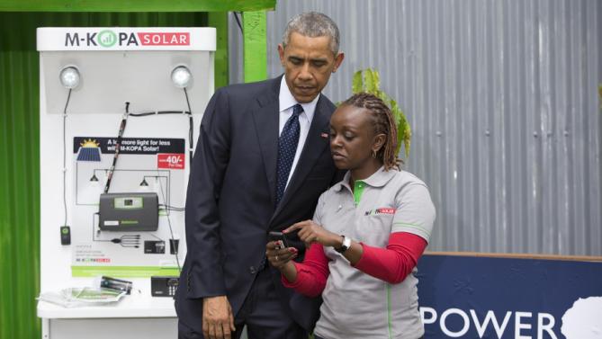 President Barack Obama looks at a mobile payment platform and solar exhibit during the Power Africa Innovation Fair, Saturday, July 25, 2015, in Nairobi. Obama's visit to Kenya is focused on trade and economic issues, as well as security and counterterrorism cooperation.  (AP Photo/Evan Vucci)