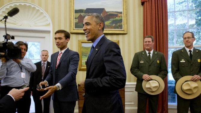 White House press assistant Peter Velz, left, gestures to make a path for President Barack Obama, center, as the president walks away from his desk after designating three new national monuments; Berryessa Snow Mountain in California, Waco Mammoth in Texas, and the Basin and Range in Nevada, in the Oval Office of the White House Friday, July 10, 2015, in Washington. At right are Behind him from left are John "Russ" Whitlock, with the National Park Service, and Victor Knox, associate director of park planning, facilities and lands of the National Park Service. (AP Photo/Jacquelyn Martin)