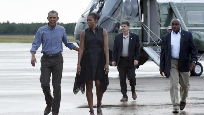 President Barack Obama and first lady Michelle Obama walk over to greet people before boarding Air Force One at Air Station Cape Cod, in Mass., Sunday, Aug. 23, 2015. The president is returning to Washington after he and his family spent more than two weeks vacationing on the Massachusetts island of Martha's Vineyard. (AP Photo/Susan Walsh)