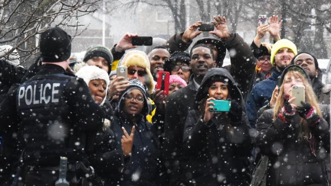 As the snow falls, surprised onlookers try to see President Barack Obama as he visits retail store Shinola in Detroit, Wednesday, Jan. 20, 2016. (Daniel Mears/Detroit News via AP, Pool)