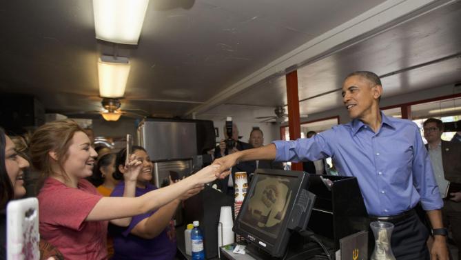President Barack Obama reaches over the counter to greet employees during an unannounced stop at Torchy's Tacos, Friday, March 11, 2016, in Austin, Texas. Obama traveled to Austin, to speak at South by Southwest Festival (SXSW) and attend 2 Democratic National Committee fundraisers. (AP Photo/Pablo Martinez Monsivais)