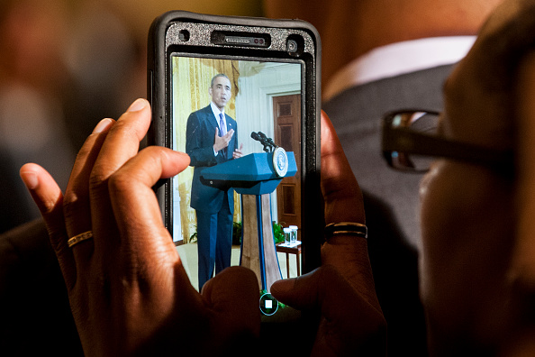 A woman photographs President Barack Obama as he delivers remarks at a reception in the East Room of the White House in recognition of LGBT Pride Month on June 9, 2016 in Washington, D.C. Photo by Pete Marovich/UPI/POOL