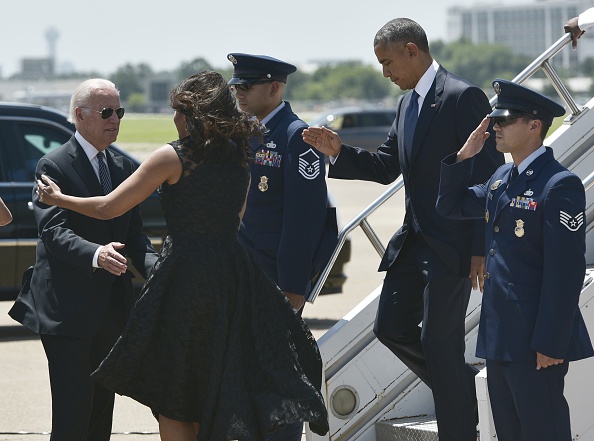US Vice President Joe Biden (L), receives a hug from First Lady Michelle Obama as US President Barack Obama steps off Air Force One upon arrival at Dallas Love Field in Dallas, Texas on July 12, 2016. / AFP / MANDEL NGAN (Photo credit should read MANDEL NGAN/AFP/Getty Images)